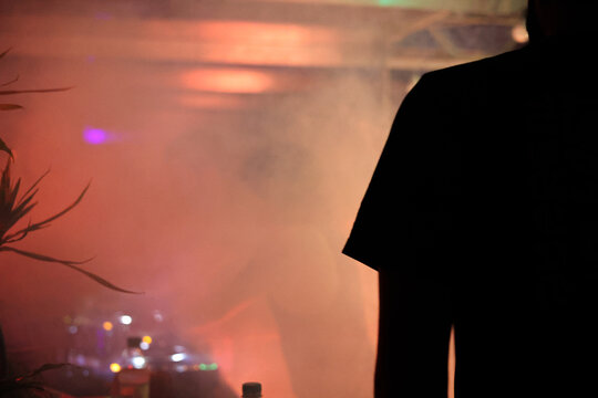 Anonymous man silhouette wearing T-shirt at party environment with fog