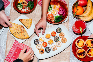 Hands reaching for food at dinner table