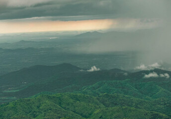 a green mountain range with a rain cloud in the background