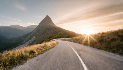 road on a hillside near mountain peak at sunset