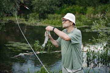 Fisherman with fishing rod near the lake at summer