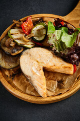 Salmon steak with grilled vegetables on a wooden plate, healthy and delicious dining option