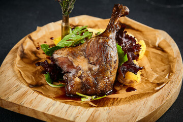 Duck leg confit with baked apples, presented on a wooden cutting board, top view. A delicious fusion of rich flavors and rustic charm