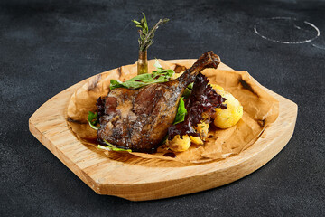Duck leg confit with baked apples, presented on a wooden cutting board, top view. A delicious fusion of rich flavors and rustic charm