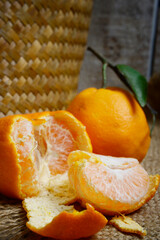 Tangerines or mandarin oranges (Citrus reticulata) are oranges that can grow in tropical and subtropical areas, randomly some are whole, some have been cut, with a natural wood and woven background