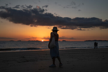 View of a female tourist on the beach against the sunset