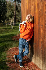 Happy guy basks in warm rays of sun while walking outdoor. Cheerful long-haired blond man leaning...