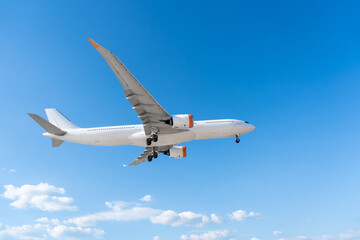 Airplane passenger plane with landing gear extended flying on blue sky, side view