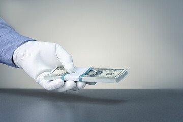 Hand in white glove holding money. Bank employee holds dollar banknotes. Corruption concept and bribery.