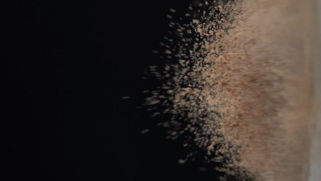 Bouncing cocoa powder in the air against black background