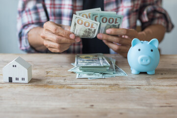 Hand's man holding money behind small house,saving concept,soft focus.
