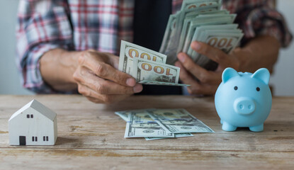 Hand's man holding money behind small house,saving concept,soft focus.