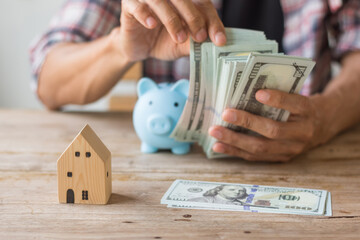 Hand's man holding money behind small house,saving concept,soft focus.