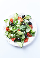 Salad with black Olives, cherry Tomatoes, Cucumber and Rocket on bright Background. Close up.
