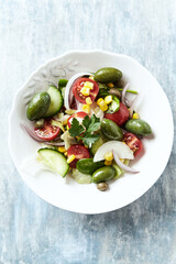 Simple Salad with Green Olives, Cucumber, Cherry Tomatoes and Capers. Bright wooden background. Top view.