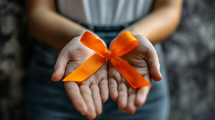 Orange ribbon in womans hands Symbol of leukemia multiple sclerosis and kidney cancer awareness