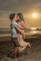 Man holding and kissing his girlfriend on the beach at sunset