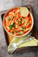 Crock Pot Salsa Chicken with taco seasoned pulled chicken breasts and tomato salsa close-up in a bowl on a wooden board. Vertical top view from above