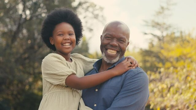Close up of smiling loving grandfather cuddling laughing granddaughter outdoors in countryside enjoying nature- shot in real time