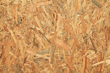 Wood (wooden) surface, texture, background. Building board made from pressed wood chips. A wall with a chaotic pattern created by press machines. Recyclable material technology. Fence, wall backdrop