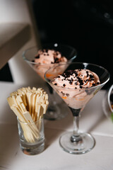 Elegant Martini Glass Desserts with Chocolate Shavings. Chic martini glasses filled with whipped cream and topped with chocolate shavings, accompanied by stir sticks.