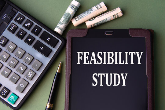 FEASIBILITY STUDY - words in an electronic notebook on the background of a calculator and banknotes