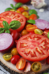 Flat lay composition of different tomatoes, onion, basil and garlic	
