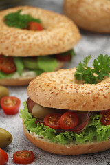Sesame bagels with tomatoes, ham and olives