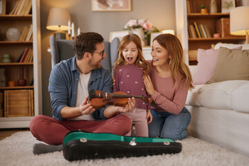 Happy family playing violin together at home