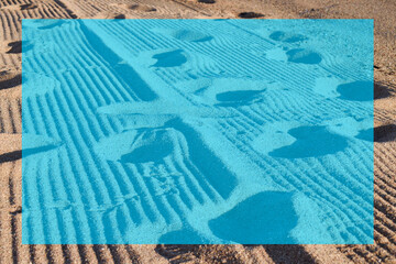 Obraz premium Sand footprints on the beach on a blue background with a reserved and light brown box.