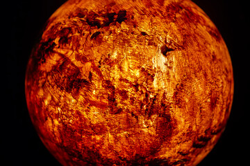 A mock-up of the planet Mars illuminated from the inside on a dark background.
