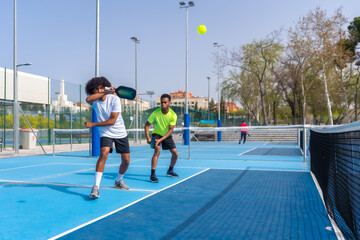 Naklejka premium African sportive friends playing pickleball together outdoors