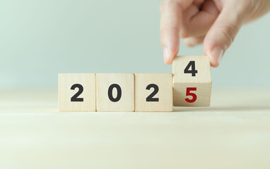 Starting new year 2025. Flipping of 2024 to 2025 on wooden cube blocks. Beginning and start of the...