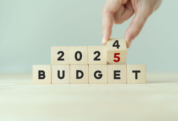 2025 Budget planning and allocation concept. Hand flips wooden cube and changes the inscription "BUDGET 2024" to "BUDGET 2025" with grey background, copy space. Use for banner and presentation.