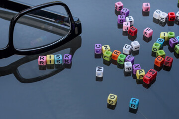 Risk and business concept. The word RISK on colorful cubes on the glass table.