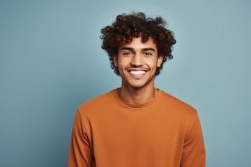 Fototapeta na wymiar A man with curly hair is smiling and wearing an orange shirt