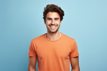A man in an orange shirt is smiling and looking at the camera