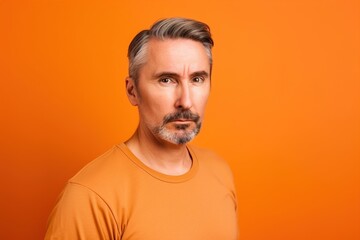 Obraz premium A man with a beard and gray hair is wearing an orange shirt