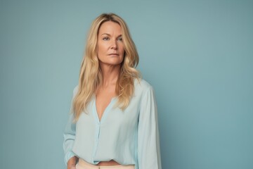 A woman in a blue shirt and white skirt is standing in front of a blue wall