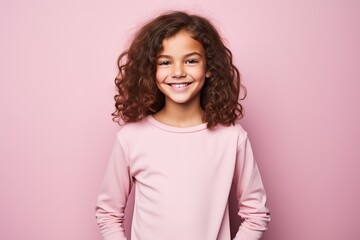 Fototapeta premium A young girl with curly hair is smiling and wearing a pink shirt