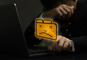A man is typing on a laptop with a yellow face on the screen