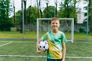 portrait of a football player boy with a ball on a football field