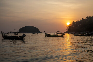 Beautiful sunset on the island of Phuket. The sun is setting. Colorful sky. Silhouettes of boats in the water.