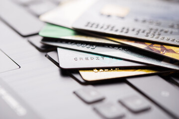 Colorful stack of credit cards and shopping gift cards on laptop keyboard. Selective focus. Macro...