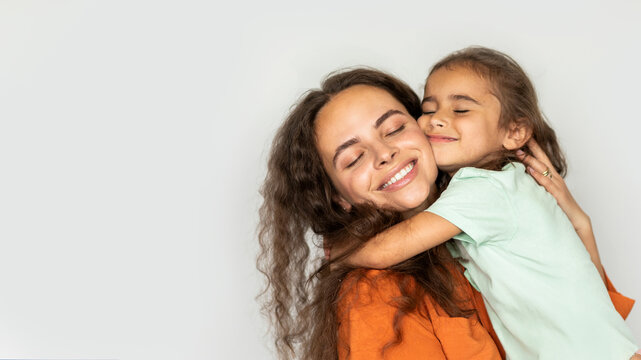 Happy young mother hugging with her daughter, family of two mom and female kid bonding, white background, panorama with copy space