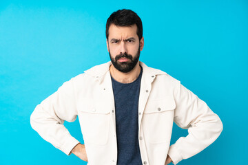 Young handsome man with white corduroy jacket over isolated blue background angry