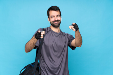 Fototapeta premium Young sport man with beard over isolated blue background points finger at you while smiling