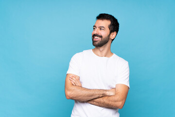 Young man with beard  over isolated blue background happy and smiling