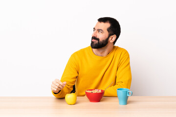 Caucasian man having breakfast in a table having doubts while looking side.