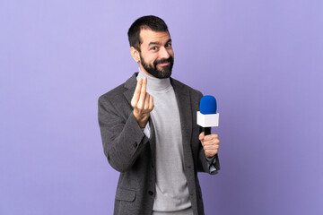 Adult reporter man with beard holding a microphone over isolated purple background making money gesture